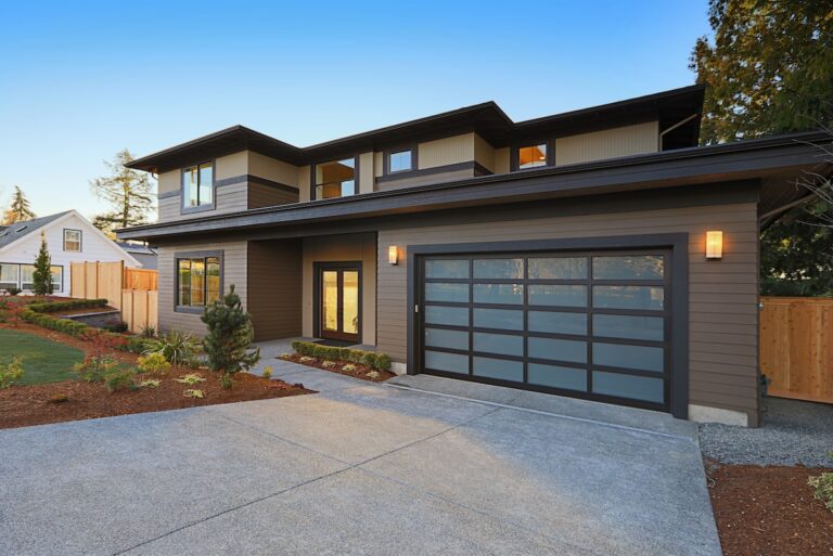 New construction home exterior with contemporary house plan features low slope roof, brown siding and glass garage door.