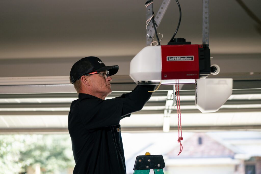 garage door tune up worker using black cap and clothes fixing door